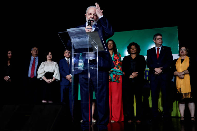 Presidente Lula, homem branco, diante de ministros. veem-se quatro brancos e dois negros ao fundo