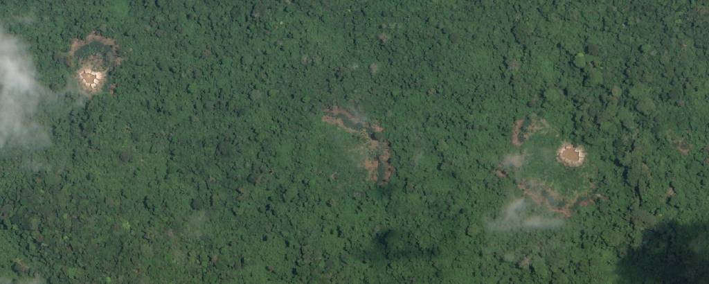 Imagem de uma floresta, vista de satélite, com tudo verde exceto um pequeno espaço de terreno desmatado, cor de terra