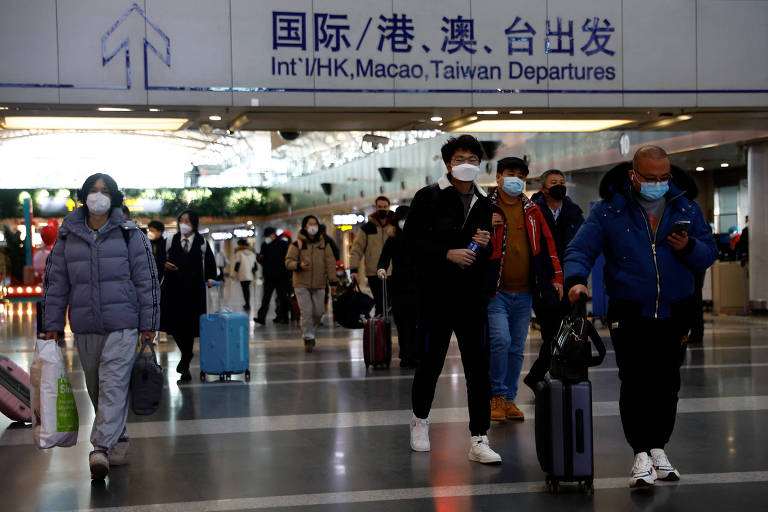 Viajantes caminham no aeroporto internacional de Pequim
