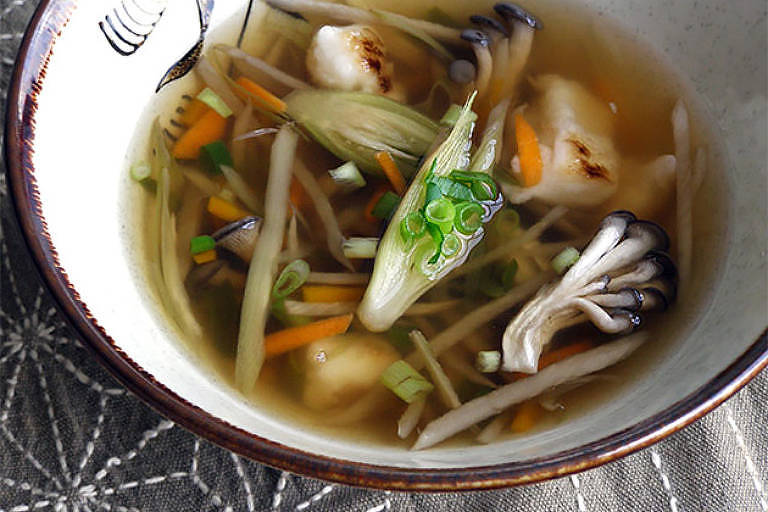 A foto mostra uma tigela com uma sopa com caldo ralo e translúcido com legumes fatiados