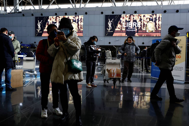Viajantes caminham no aeroporto internacional de Pequim