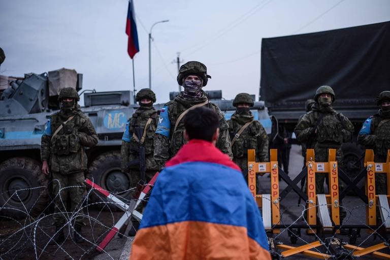 Manifestante com a bandeira da Armênia em frente às forças russas que bloqueiam a estrada de Stepanakert, capital da região de Nagorno-Karabakh