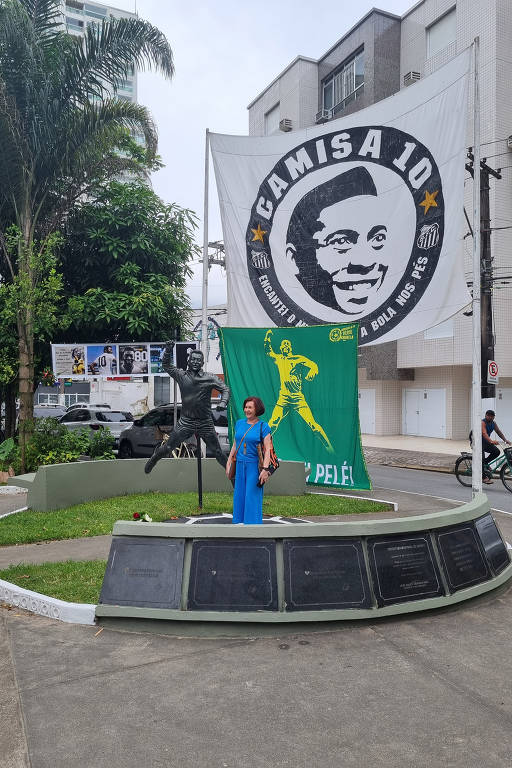 Fã tira foto junto a famosa estátua do Rei Pelé dando um soco no ar, em Santos,no bairro Aparecida