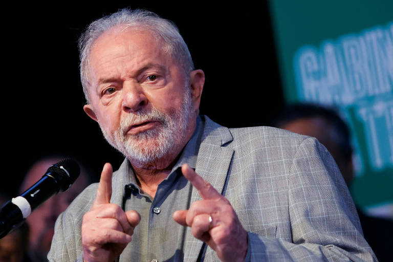 Lula está com os dedos indicadores das duas mãos levantados.