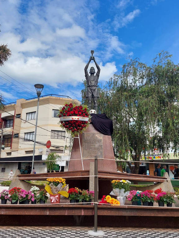 foto de estátua de pelé em praça com flores na base
