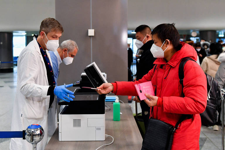 Passageira entrega passaporte a funcionário do aeroporto de Malpensa, em Milão, após desembarcar de voo vindo da China
