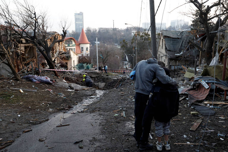 Um homem abraça seu filho onde um míssil russo caiu em Kiev, na Ucrânia
