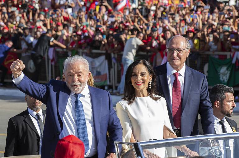 Lula, um homem branco de cabelo e barba branca, comemora a posse durante desfile em veículo aberto