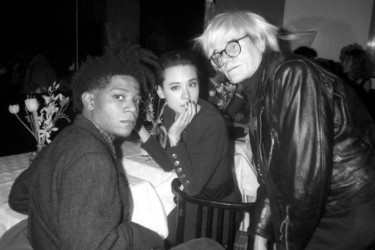 Na Nova York dos anos 1980, os artistas plásticos eram assediados pela imprensa como estrelas do rock. Basquiat e Warhol eram parte deste seleto grupo que era presença constante em festas e coquetéis. Na foto, eles aparecem com a modelo Tina Chow