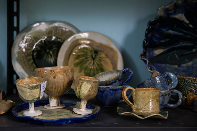 Imagem colorida mostra copos, pratos e xícaras de cerâmica, em uma cor predominante marrom, em cima de uma mesa