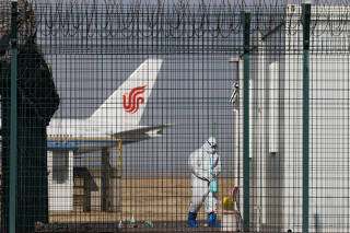 A worker in a protective suit walks near a plane of Air China airlines at Beijing Capital International Airport as coronavirus disease (COVID-19) outbreaks continue in Beijing