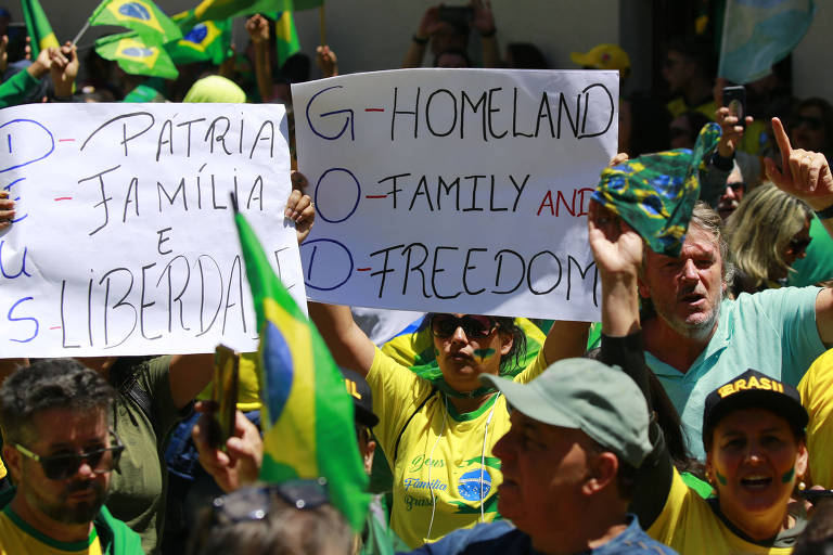 Várias pessoas de verde e amarelo com bandeiras do Brasil e cartazes com os dizeres "Deus, Pátria, Família e Liberdade" e "God: homeland, famly and freedom"