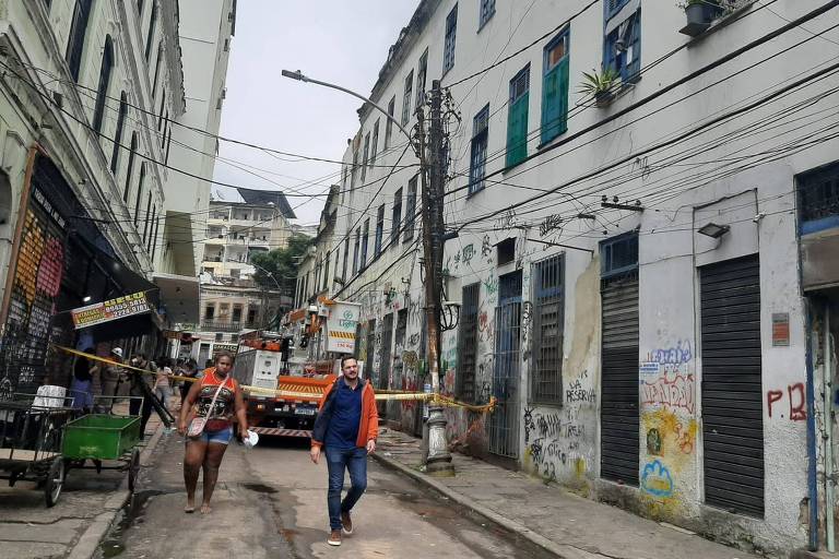 Pessoas em frente a faixa de interdição da rua em que um prédio desabou no Rio de Janeiro