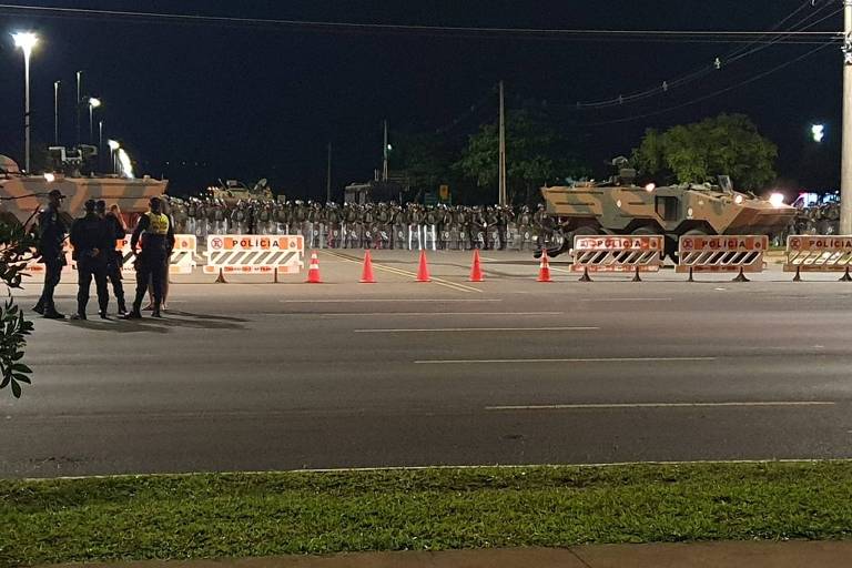 Um cordão de soldados da Polícia do Exército obstrui a entrada na rua que dá acesso ao quartel-general do Exército, em Brasília. Na foto, é possível ver blindados estacionados para impedir a passagem de veículos.