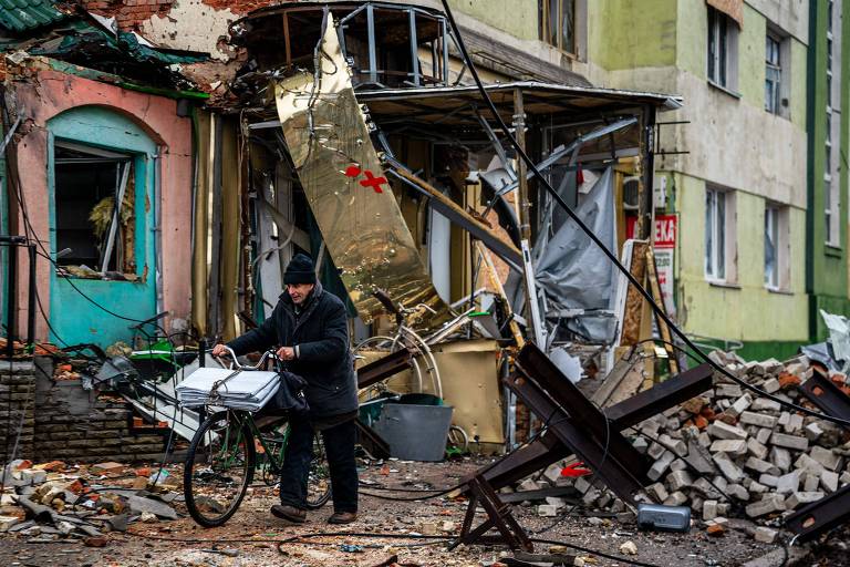 Morador de Bakhmut passa por casa destruída na cidade, alvo dos russos em Donetsk