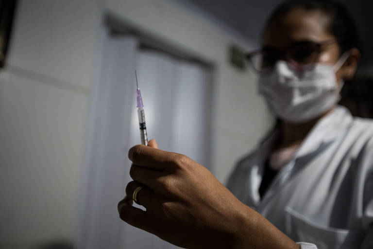 Enfermeira segura seringa para aplicação de vacina
