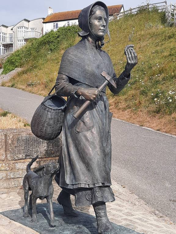Estátua de Mary Anning e seu cão, Tray, na cidade de Lyme Regis, no sul da Inglaterra. A estátua foi produzida por Denise Dutton e colocada na cidade na ocasião da Campamnha "Mary Anning Rock", em 2022.