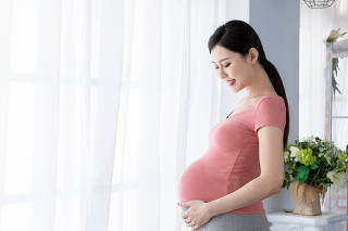 Side,View,Of,Beautiful,Asian,Pregnant,Woman,Standing,Near,Window