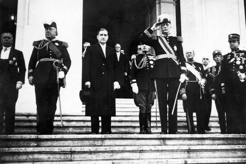 (FILES) In this file photo taken on November 30, 1938 Portuguese President Oscar Carmona (R) and Portuguese Prime Minister Antonio de Oliveira Salazar (C) listen to national anthem during the reopening of the National Assembly in Lisbon. - Portugal will mark the 48th anniversary of the Carnation Revolution on April 25, 2022. The revolution was made by a group of officers and his chief strategist Otelo Saraiva de Carvalho organised in the Movement of Armed Forces (MFA). After the military coup, Portuguese regime changes from a dictatorship, founded by Antonio de Oliveira Salazar and called Estado Novo, to a democracy. (Photo by FRANCE PRESSE VOIR / AFP)