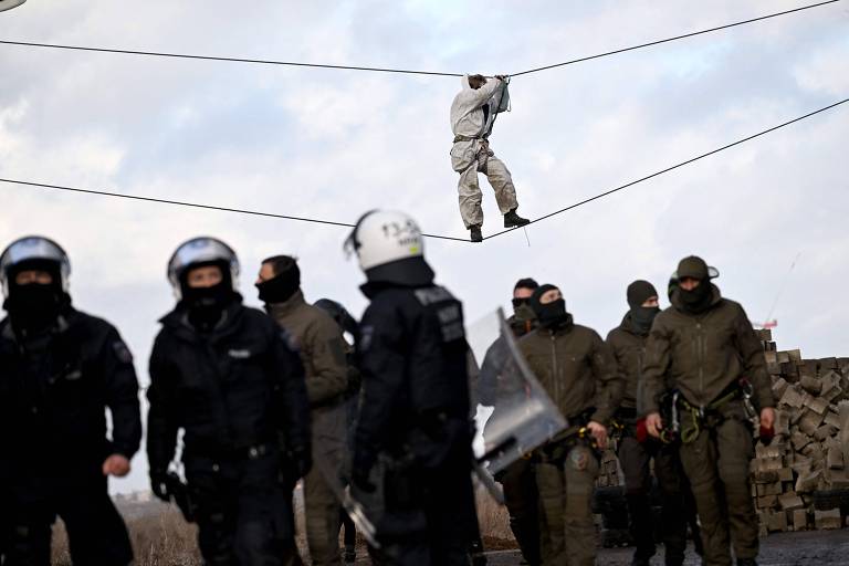 Ativista se equilibra em cabos em Lützerath, no oeste da Alemanha, para evitar ser pego por policiais após ordem de retirada do vilarejo