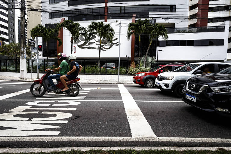 Motoqueiro aguarda abertura de sinal em faixa reservada para motocicletas em avenida de Aracaju, Sergipe