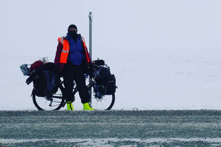 Ciclista muito agasalhada em paisagem de neve