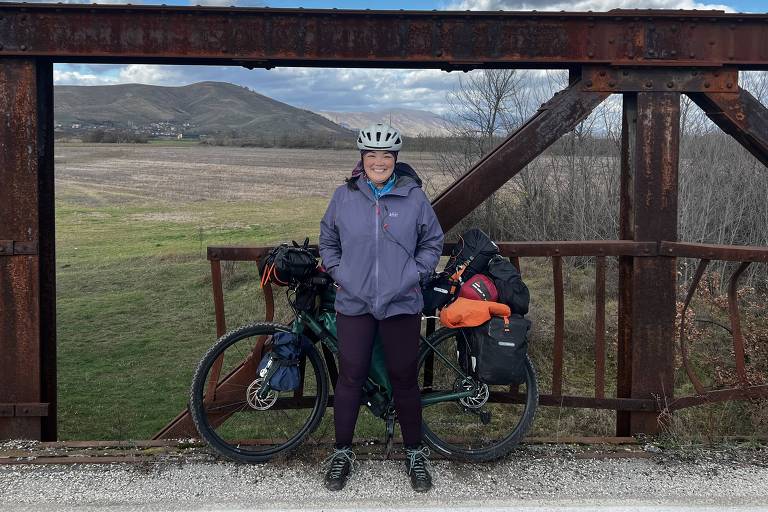Ciclista e sua bike em paisagem de uma ponte de ferro