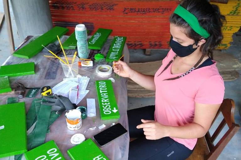 Natachi Silva, pintando placas de sinalização, em ação de voluntariado