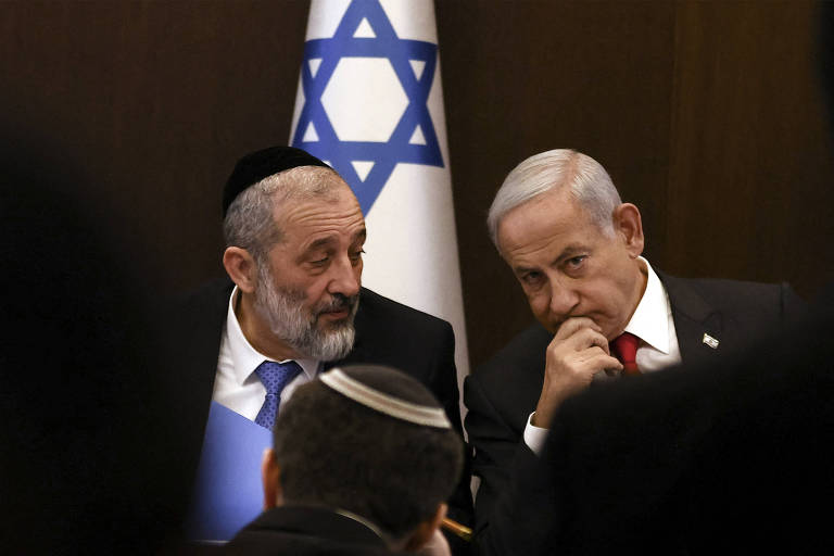 O premiê de Israel, Biyamin Netanyahu, à dir., ao lado do até então ministro do Interior e da Saúde, Aryeh Deri, durante reunião em Jerusalém