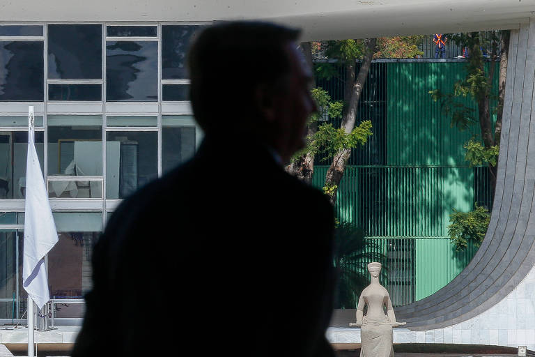 Foto mostra silhueta de Bolsonaro diante do prédio do STF, que aparece ao fundo, com a estátua da Justiça