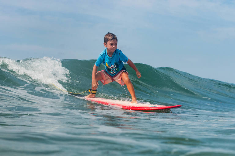 criança de 5 anos aprendendo a surfar