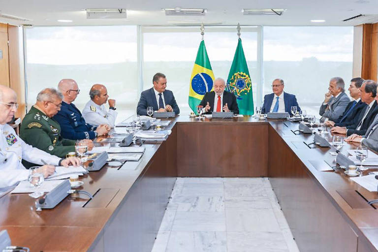 Sala com mesa com três bancadas, ao fundo, está o presidente Lula, entre os demais homens presentes, estão os comandantes das Forças Armadsa vestindo uniforme