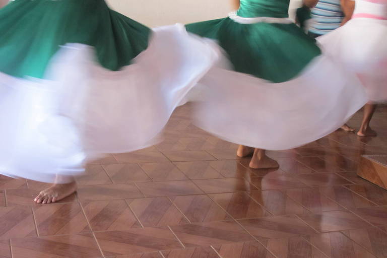 Duas saias em movimento, nas cores verde e branco, deixam à mostra os pés de participantes da cerimônia religiosa do Terecô, no Maranhão