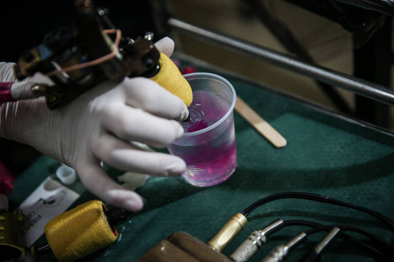 Uma máquina com agulha de atuar, que é posta em um copo de plástico com uma solução roxa