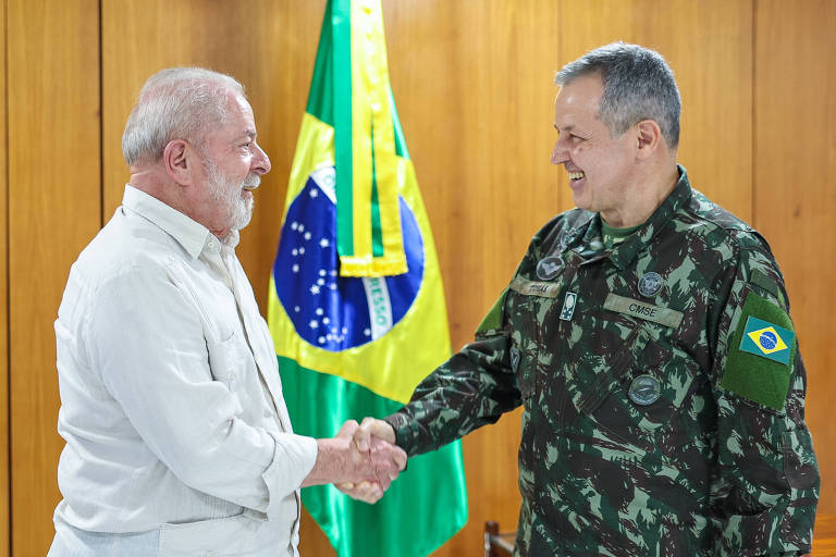 Lula, de camisa branca, cumprimenta com aperto de mãos o comandante do Exército, de farda, ambos sorriem