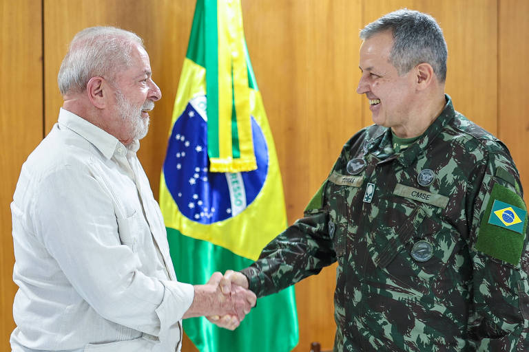 Lula, de camisa branca, cumprimenta com aperto de mãos o comandante do Exército, de farda, ambos sorriem