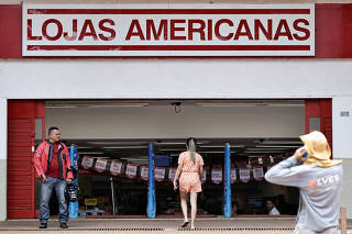 FILE PHOTO: FILE PHOTO: People walk in front of a Lojas Americanas store in Brasilia
