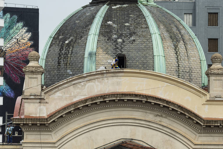 Trabalhador realiza trabalho de restauro no telhado da cúpula do Mercadão de SP