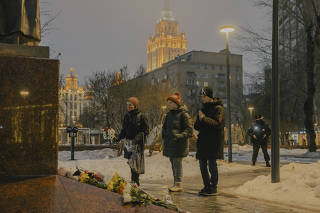 People lay flowers at the statue of the Ukrainian poet and writer Lesya Ukrainka in Moscow, on Jan. 19, 2023, in memoriam to those killed by a Russian missile strike in Dnipro, Ukraine. (Nanna Heitmann/The New York Times)