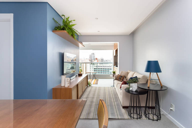Sala de estar com duas paredes perpediculares pintadas com o mesmo tom de azul