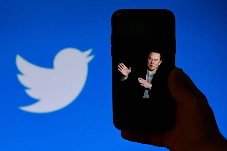 No detalhe, pessoa segura celular com a foto do bilionário Elon Musk ao lado do símbolo do Twitter