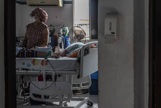 Suhellen Oliveira Da Silva, whose children both have the rare genetic disorder spinal muscular atrophy (SMA), holds 2-year-old Levi while a nurse tends to her older son Lorenzo, 10, in a bedroom at their home on the outskirts of Recife, Brazil, June, 4, 20