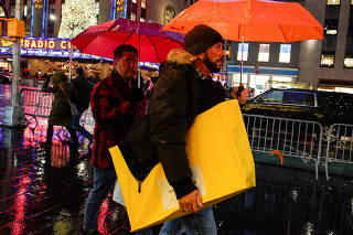 FILE PHOTO: A man walks under the rain with his shopping bag during the holiday season in New York