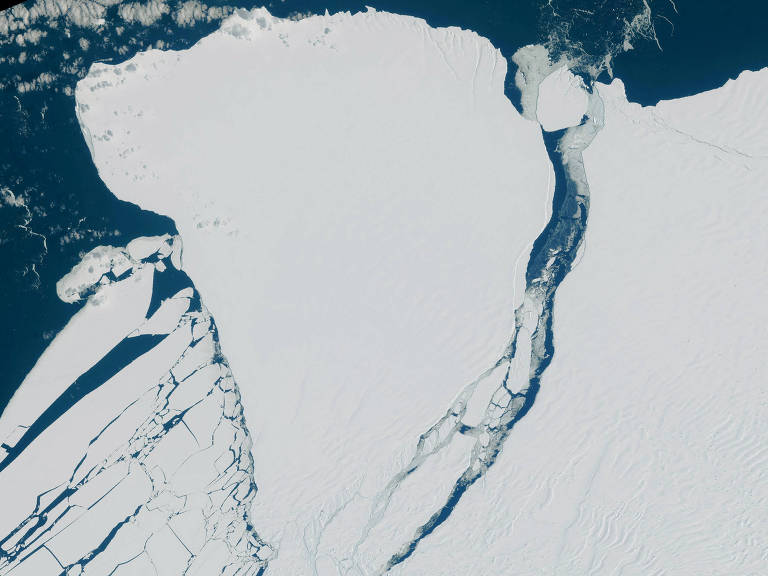 Vista aérea de um bloco gigante de gelo branco se soltando no oceano antártico, azul escuro