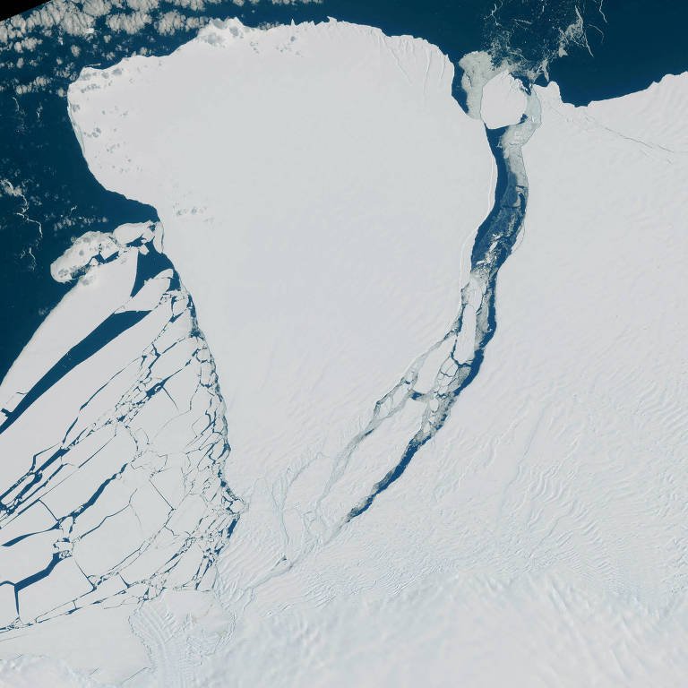 Plataforma de gelo, toda branca, é vista de cima após rompimento de iceberg sobre o mar azul escuro