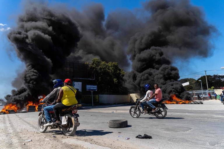 Motociclistas próximos de pneus incendiados durante protesto em Porto Príncipe, no Haiti