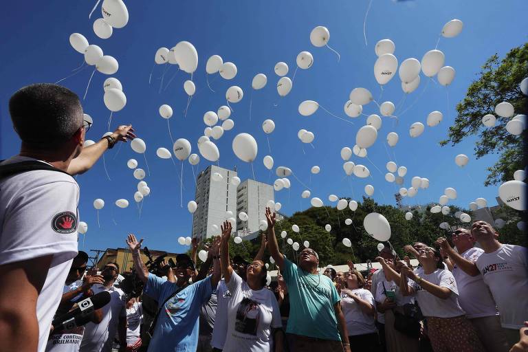 Manifestantes soltam balões brancos, que voam sob um céu azul