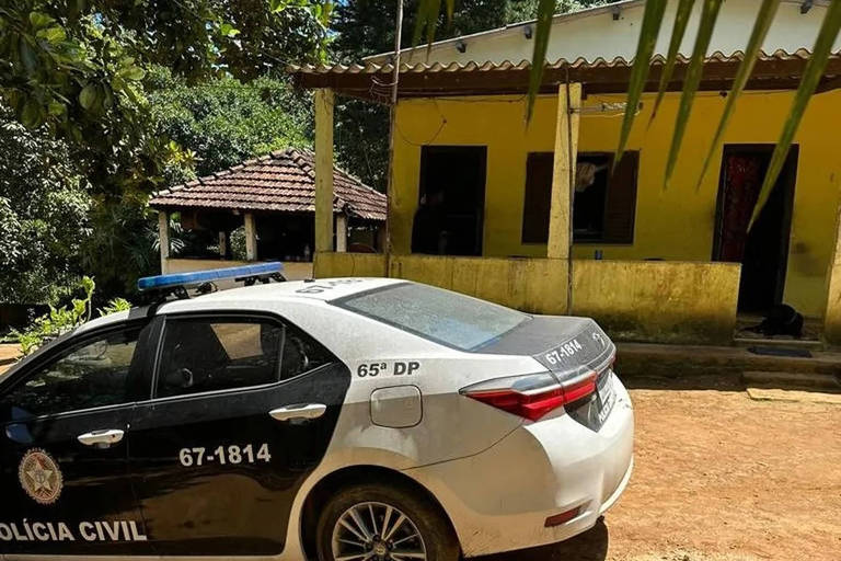 Imagem colorida mostra carro da Polícia Civil em frente à uma casa antiga com tintura amarela