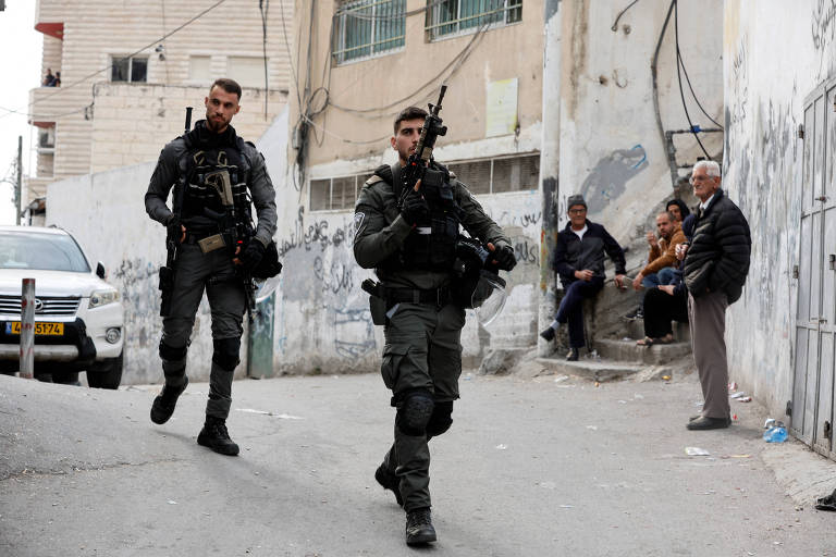 Policiais israeleneses caminham em frente à casa de atirador palestino em Jerusalém Oriental