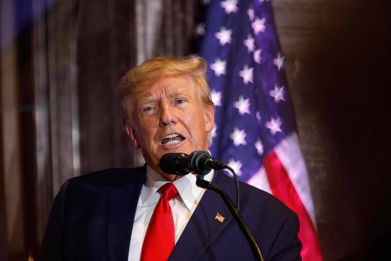 Homem engravatado, o ex-presidente Donald Trumpo, fala em frente a um microfone 
